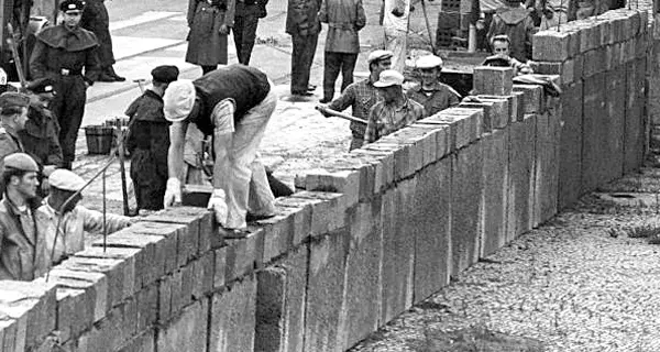 Unter der Aufsicht von bewaffneten Volkspolizisten errichtet eine Ostberliner Maurerkolonne am Potsdamer Platz eine mannshohe Mauer. Quelle: dpa - Bildarchiv. Fotograf: UPI. 