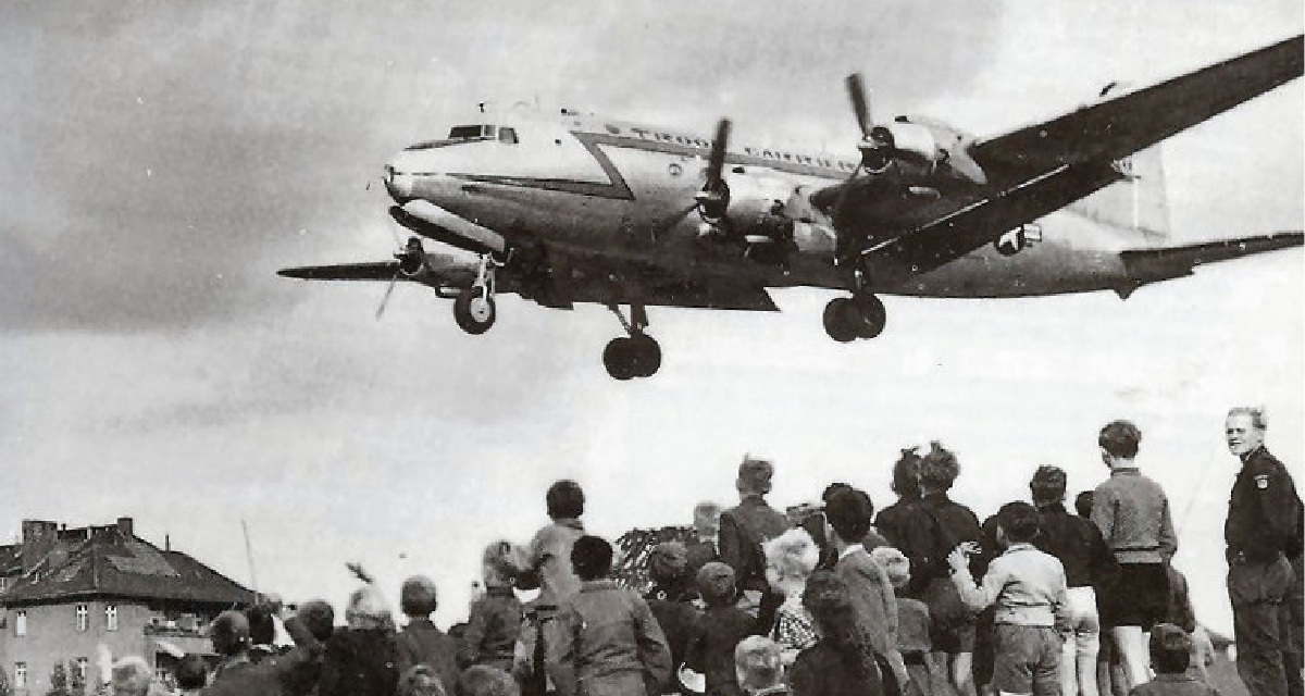 Berliners beobachten die Landung eines C-54-Flieger auf dem Tempelhofer Flughafen in Berlin 1948. Foto: wikimedia / Henry Ries / USAF, gemeinfrei.
