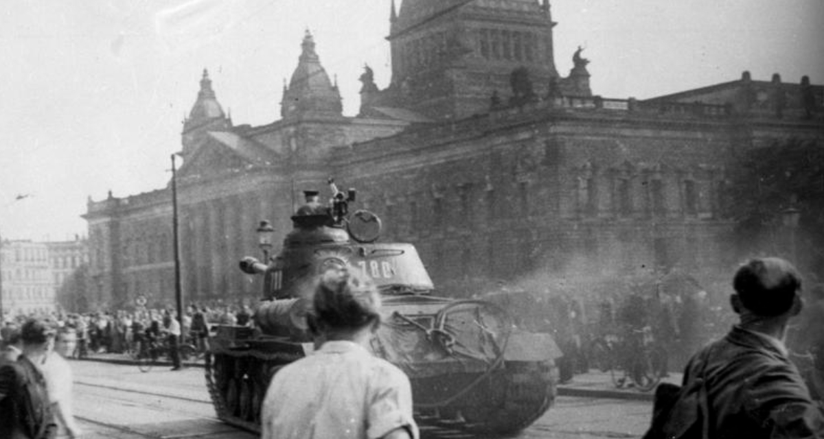 Ein russischer Panzer fährt durch die Straßen von Leipzig. Menschen stehen auf dem Bürgersteig und schauen zu.