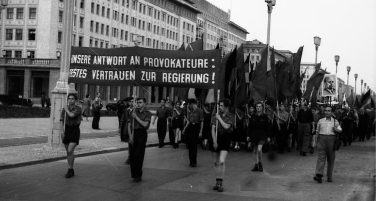 Arbeiterinnen und Arbeiter laufen mit Plakaten und Bannern durch die Berliner Straßen