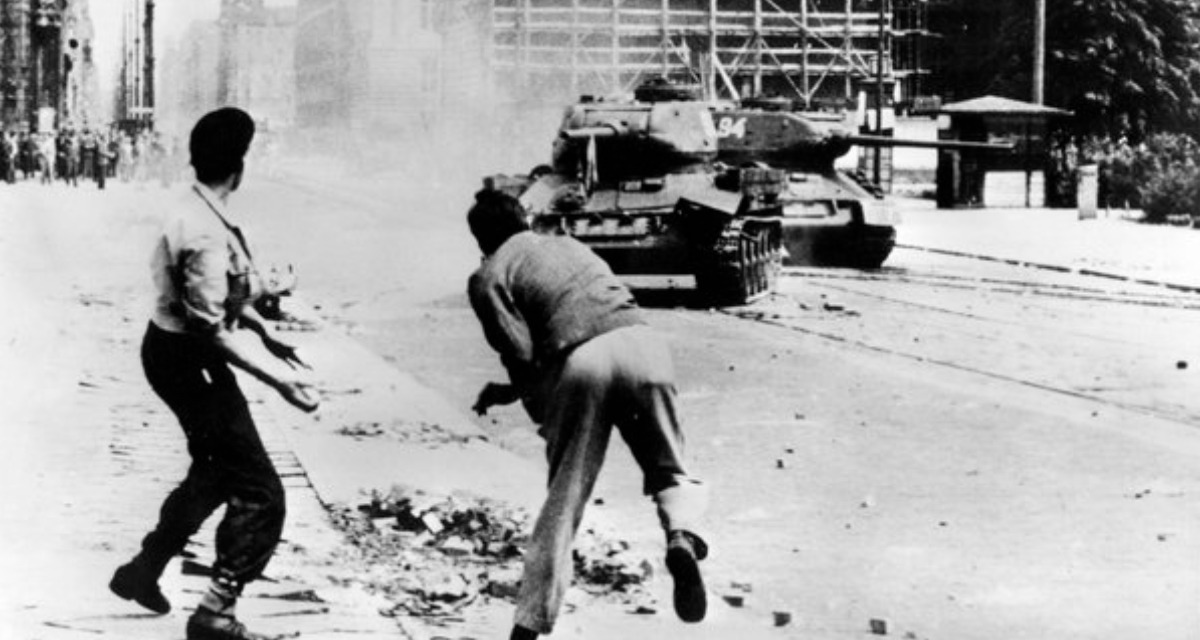 Demonstranten werfen Steine auf einen russischen T-34 Panzer in Ost-Berlin am 17. Juni 1953. Foto: picture alliance / AP Photo.